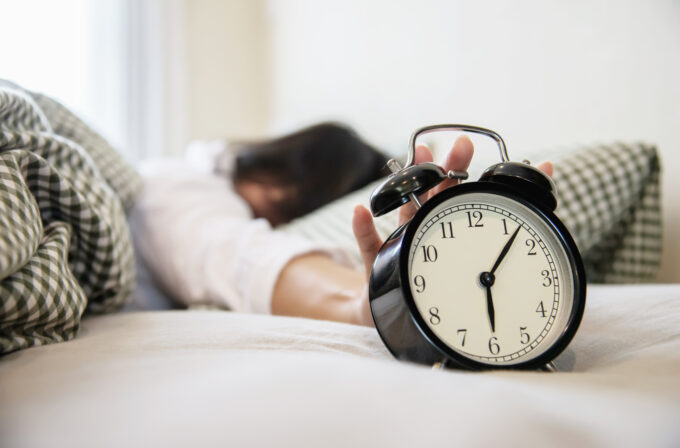Donna sul letto con una sveglia ad indicare il sonno