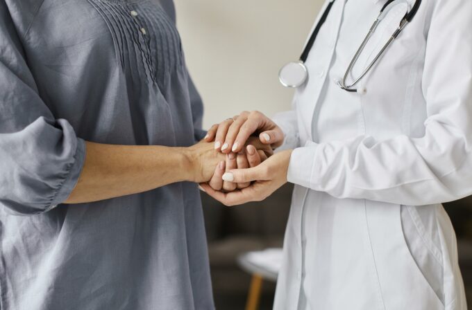 Due donne - un medico e una paziente - che si tengono per mano